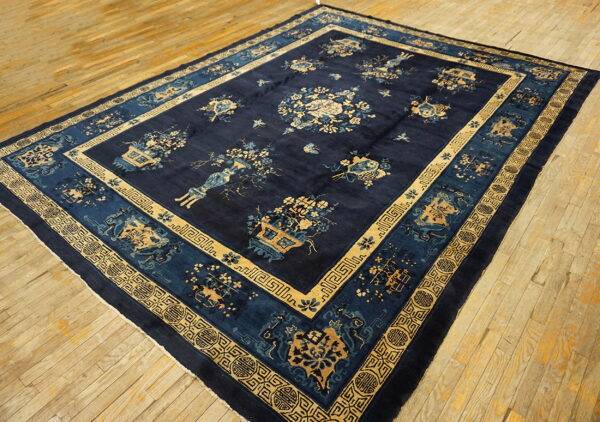 Navy blue area rug with gold and light blue botanical and geometric patterns rests on light wood planks.