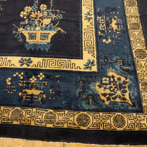 Navy rug with gold and teal botanical motifs and detailed geometric borders on light wooden flooring.