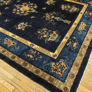 Dark navy rug featuring a traditional gold and blue botanical pattern and complex geometric borders on wood flooring.