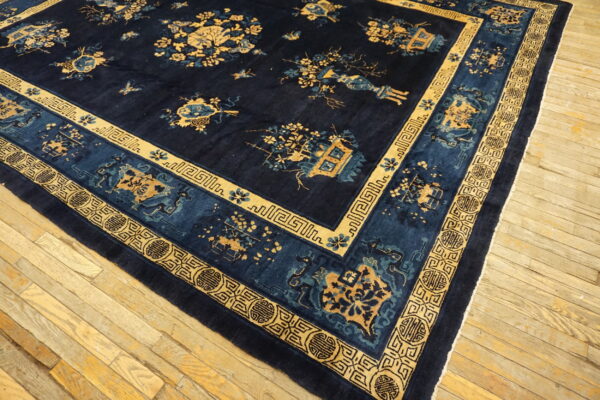 Dark navy rug featuring a traditional gold and blue botanical pattern and complex geometric borders on wood flooring.