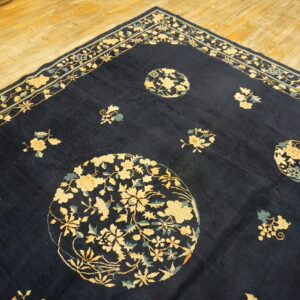 Navy blue rug with a floral border and scattered medallions in cream and light blue on wood flooring.
