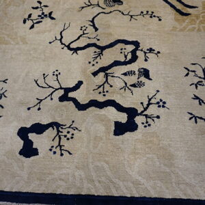 Beige rug with a dark blue scenic pattern of flowering branches and bamboo on wood flooring.