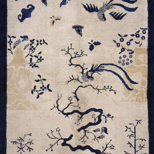 Beige rug with deep blue Chinoiserie pattern of branches, flying birds, and subtle tan clouds.