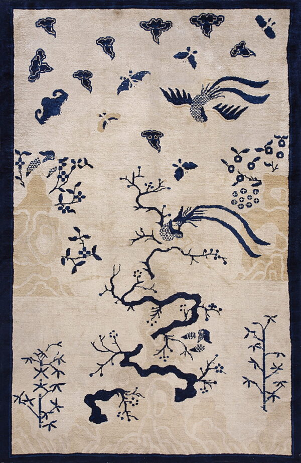Beige rug with deep blue chinoiserie pattern of branches, flying birds, and subtle tan clouds.