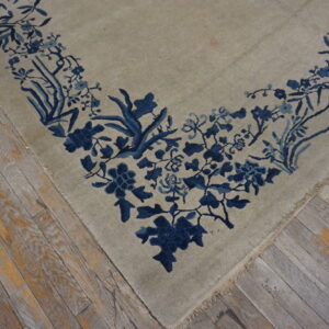 Greige rug corner with a dense indigo floral border resting on worn wooden planks.