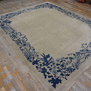 Pale beige rug featuring a detailed dark blue botanical border resting on weathered wooden planks.