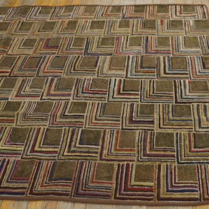 Hooked rug with a geometric block pattern featuring variegated stripes in earthy colors on wood flooring.