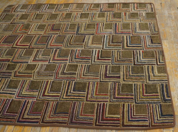 Hooked rug with a geometric block pattern featuring variegated stripes in earthy colors on wood flooring.