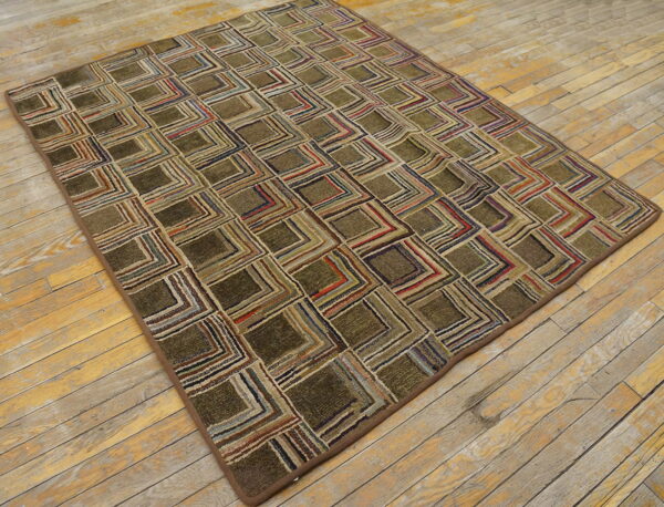 Textured olive and multicolored geometric patterned rug lying on distressed light hardwood flooring.