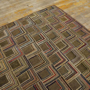 A shaggy olive-green rug with a geometric striped square pattern covers a portion of worn wood flooring.