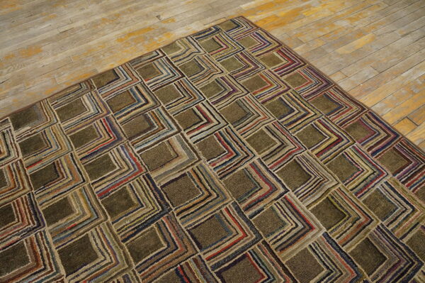 A shaggy olive-green rug with a geometric striped square pattern covers a portion of worn wood flooring.