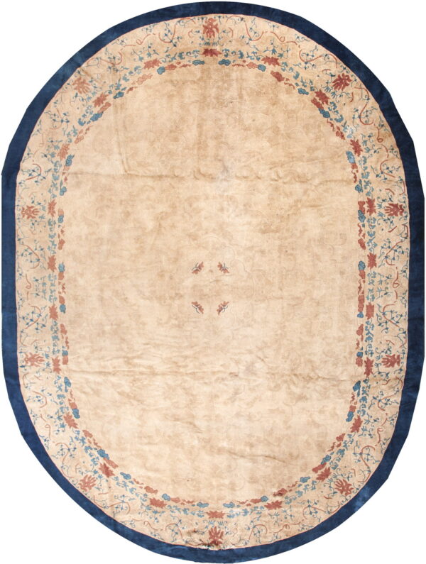Oval beige rug featuring a blue and rust floral medallion border and a solid dark blue outer edge.