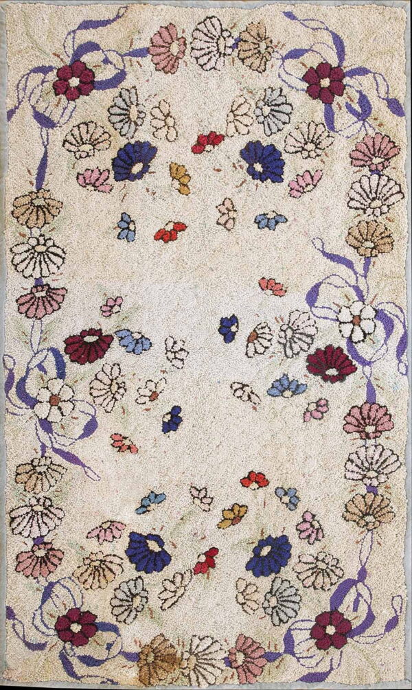 Light beige textured rug displaying a dense multicolored floral border connected by looping purple ribbons.