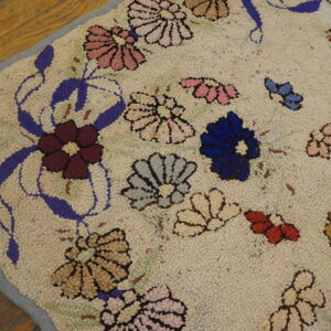 Nubby cream rug featuring multicolored pink, blue, and burgundy floral designs resting on wood planks.