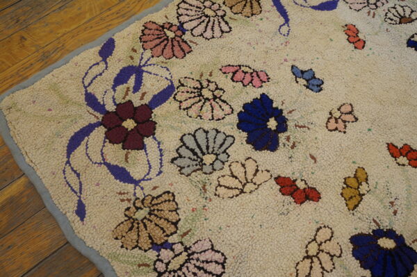 Nubby cream rug featuring multicolored pink, blue, and burgundy floral designs resting on wood planks.