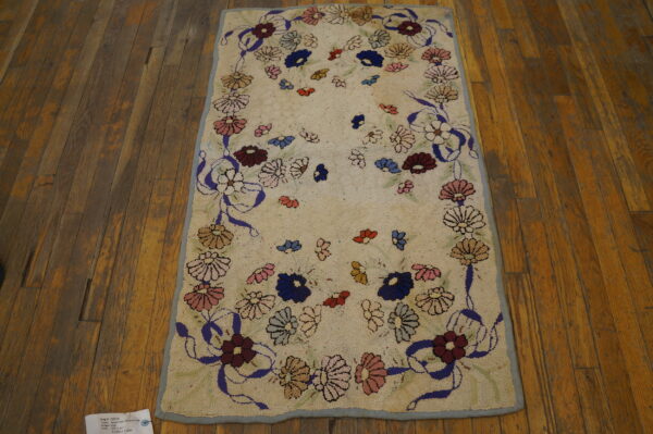 Textured cream rug with a multicolored floral and purple ribbon pattern on rustic brown wood floors.