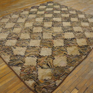 Textured, diamond-shaped rug with a beige and multicolored zigzag checkerboard design on wood floors.