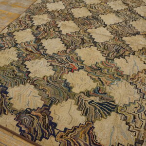 Textured beige rug with a multicolored, jagged geometric pattern rests on distressed wooden floor planks.