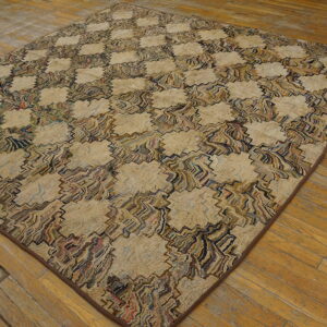 A large, textured rug with a complex beige and colorful geometric pattern lies on wide plank wood flooring.