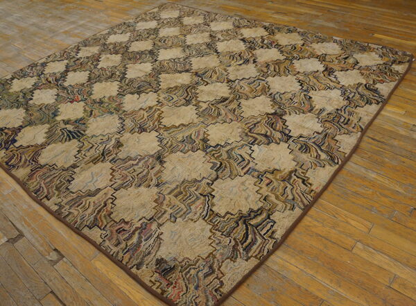 A large, textured rug with a complex beige and colorful geometric pattern lies on wide plank wood flooring.