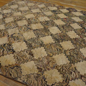 A textured rug with beige floral shapes connected by multicolored zigzagging stripes rests on wood flooring.