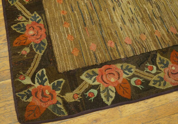 Dark brown and coral floral hooked rug border next to a textured tan field, visible on light wood planks.