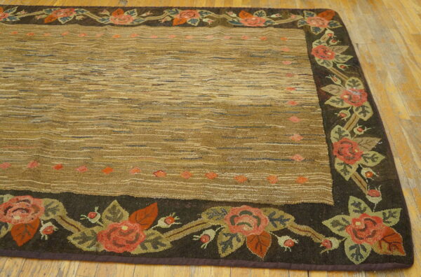 Textured tan rug with a thick, dark brown floral border lies on light plank hardwood flooring.