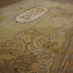 Textured olive green and beige floral rug resting on worn wooden plank flooring.