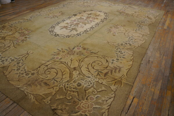 Textured olive green and beige floral rug resting on worn wooden plank flooring.