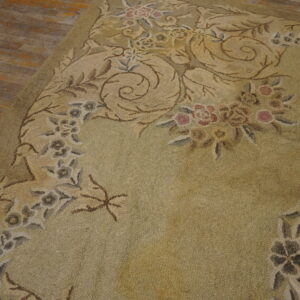 Textured sage rug with a detailed floral and vine pattern lies on distressed wooden floorboards.