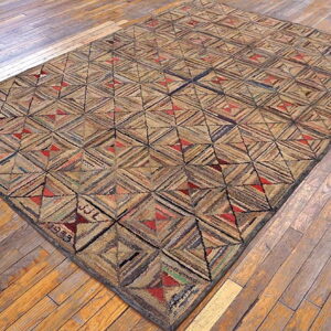Rustic low-pile rug featuring a geometric patchwork pattern of tan, brown, and red on distressed wood planks.