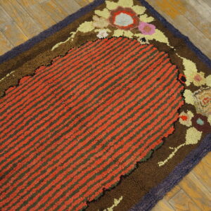 Textured rug with red striped oval center, multicolored floral border, lying on weathered wood planks.
