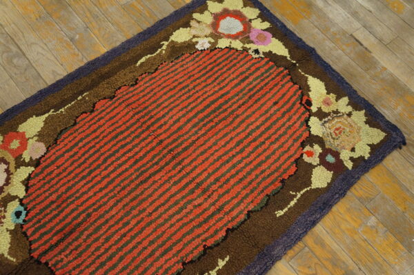 Textured rug with red striped oval center, multicolored floral border, lying on weathered wood planks.