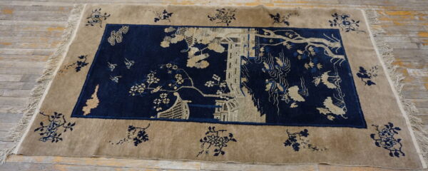 High pile rug in tan and navy blue with a detailed landscape scene on light wood floors.