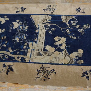 A beige border rug with navy blue center field features an intricate scenic pattern of trees, buildings, and birds.