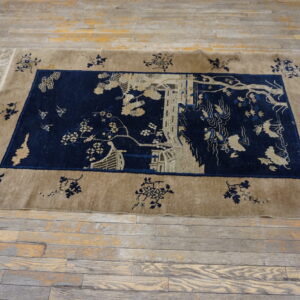 Navy field rug with a detailed tan scenic pattern and floral border on rustic wooden floorboards.