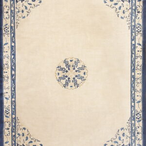 A cream rug with a geometric blue medallion and intricate blue floral border detailing.