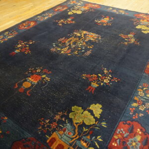 A plush navy blue rug featuring scattered colorful floral and landscape vignettes on light wood flooring.