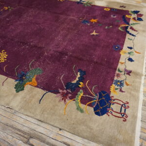 Lustrous purple rug with a multicolored floral border lies on rustic light-toned wood flooring.
