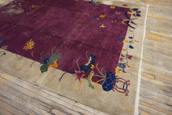 Lustrous purple rug with a multicolored floral border lies on rustic light-toned wood flooring.