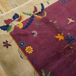 High pile burgundy rug with beige border displays colorful vines and flowers on rustic wood floor.