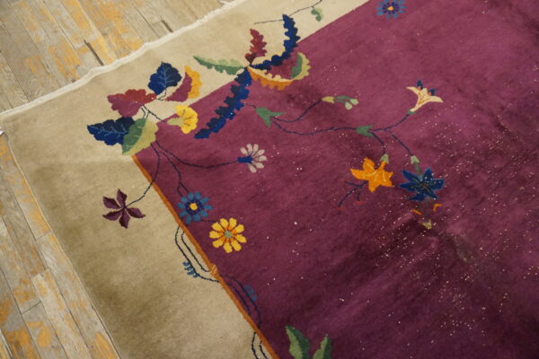 High pile burgundy rug with beige border displays colorful vines and flowers on rustic wood floor.