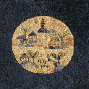 A richly textured rug features a dark background and a circular golden medallion with village scenery.