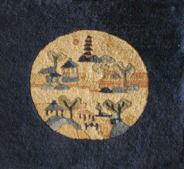A richly textured rug features a dark background and a circular golden medallion with village scenery.