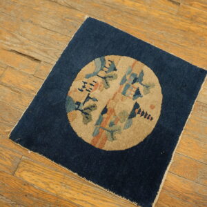 Navy rug featuring a tan central medallion with stylized blue, green, and orange designs on wood plank flooring.