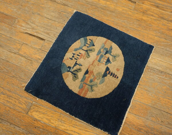 Navy rug featuring a tan central medallion with stylized blue, green, and orange designs on wood plank flooring.