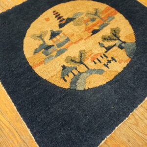 Dark blue rug square featuring a circular gold, blue, and green landscape medallion on wood floor planks.