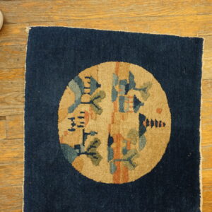 Square navy rug with a circular tan medallion featuring stylized blue, green, and orange patterns on hardwood flooring.
