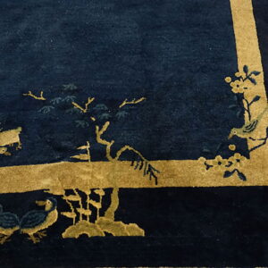 Textured dark blue rug featuring a wide gold border and stylized scenic motifs of birds and branches.