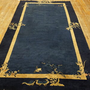 Navy blue rug on a plank wood floor has a golden border and stylized bird and floral motifs.